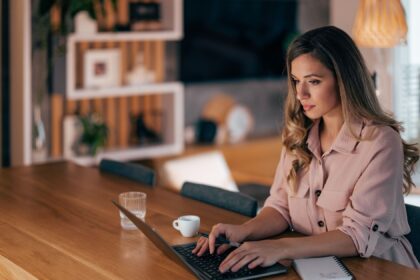 Mulher jovem trabalhando em um laptop em casa, representando o empreendedorismo e a flexibilidade de trabalhar remotamente.