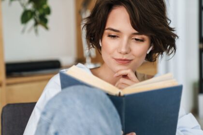 Mulher jovem lendo um livro em casa, simbolizando o aprendizado e a inspiração para empreendedores.